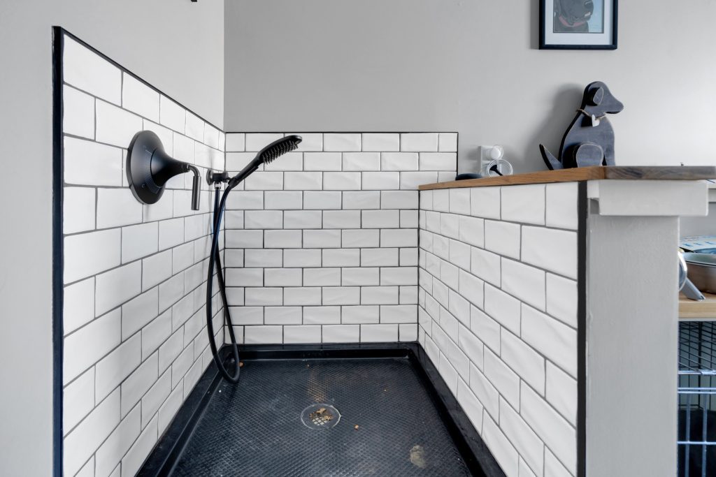 Louisville modern farmhouse bathroom with white subway tiles, black floor, and sleek handheld shower.