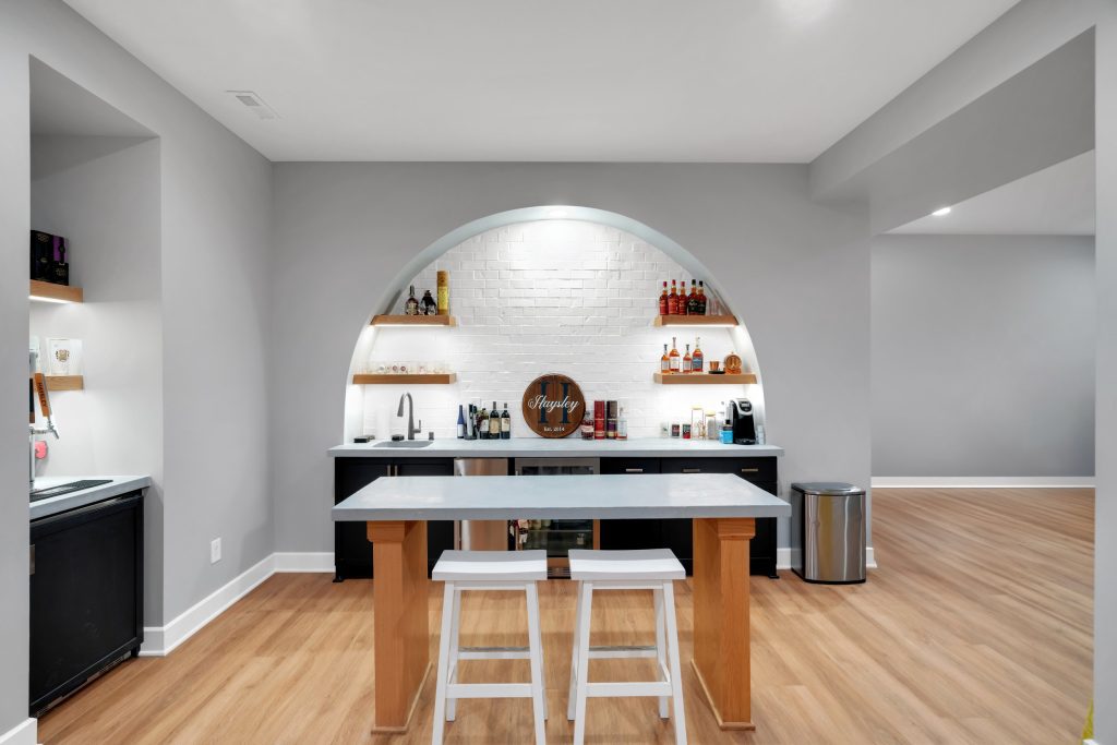 Louisville modern home bar with gray counter, white stools, and brick arch niche. Stylish and inviting.