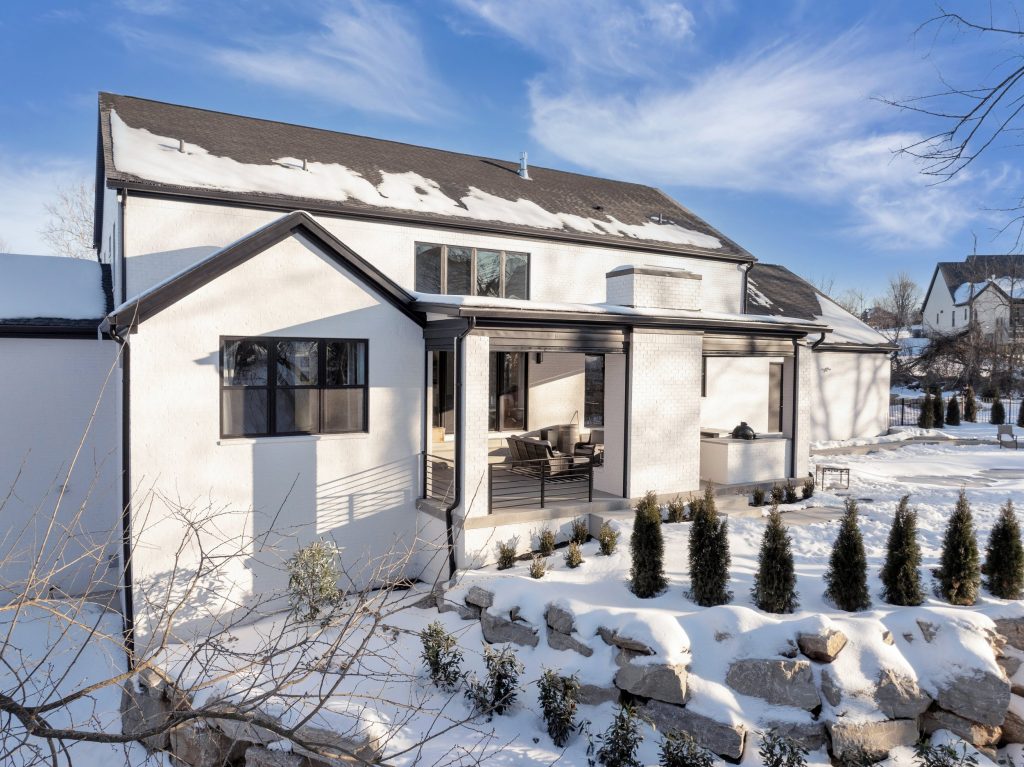 Louisville two-story home with snowy landscape and sunlit patio by top custom home builders Eldridge Company.