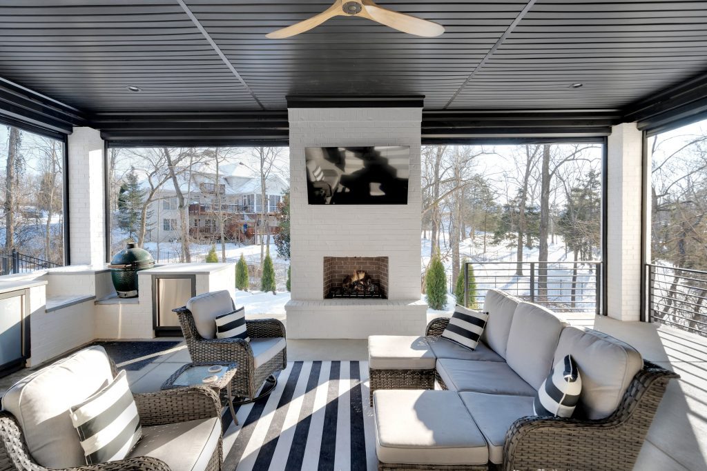 Louisville outdoor lounge by top custom home builders featuring new house ideas with wicker seating, striped rug, and winter fireplace.
