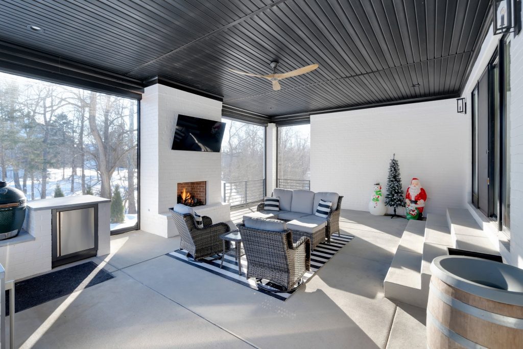 Louisville modern outdoor lounge with fireplace, TV, and festive decor by top custom home builders