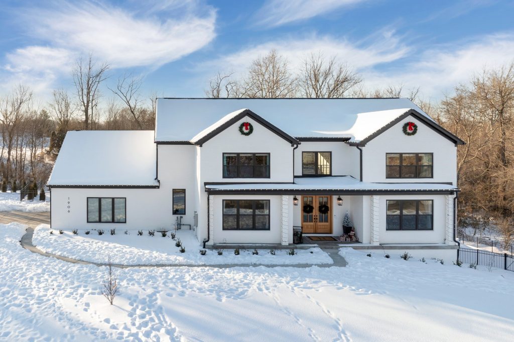 Louisville two-story white home with black trim and wreaths, snowy landscape, by top custom home builders Eldridge Company.