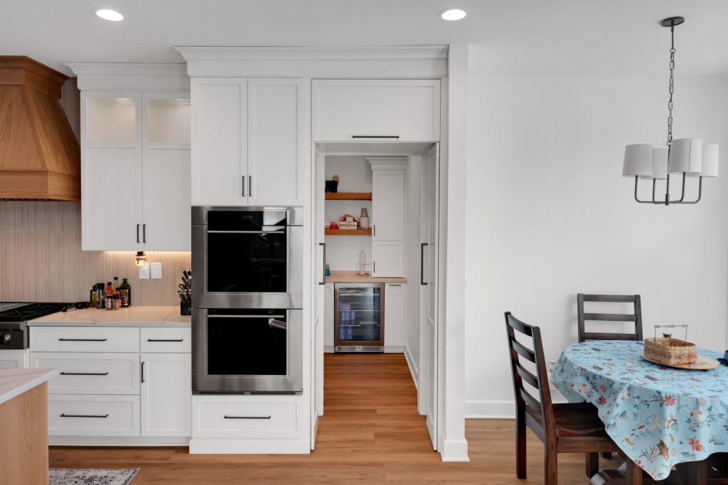 Bright Louisville kitchen with sleek white cabinets, open shelving, wine fridge, and inviting pantry space by top custom home builders