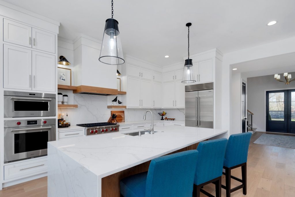 Louisville modern kitchen with marble island, blue chairs, and pendant lights by top custom home builders Eldridge Company.
