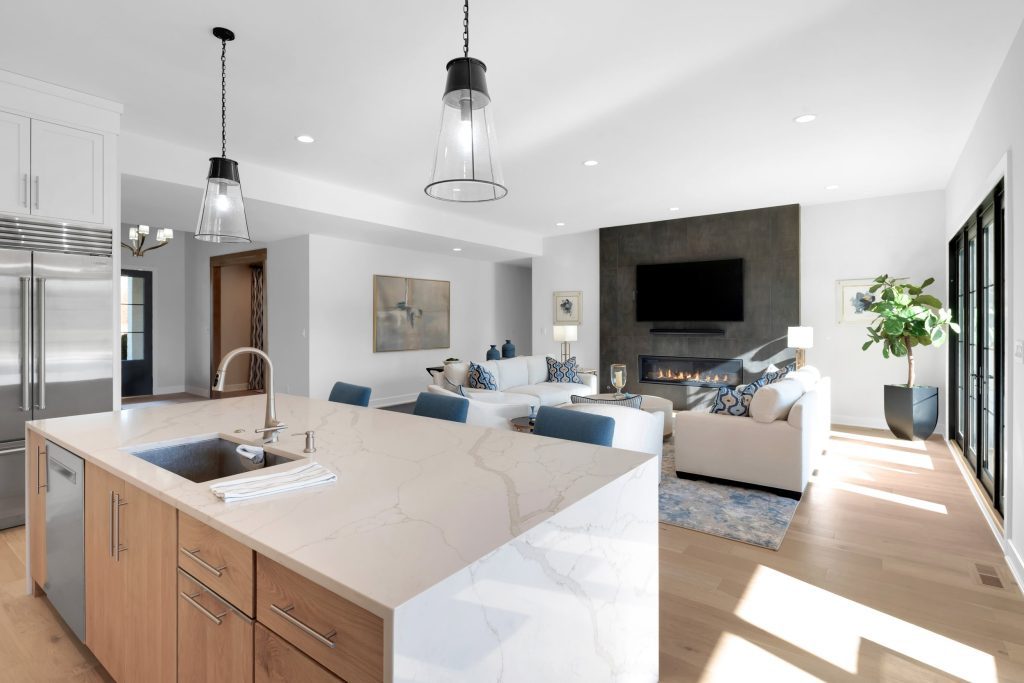Louisville modern living room and kitchen with open layout, marble island, and pendant lights by top custom home builders Eldridge Company.