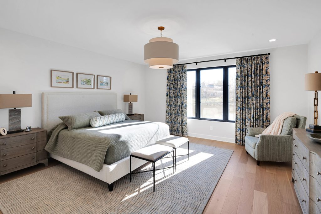 Louisville modern bedroom with large bed, gray bedding, and sunlight by top custom home builders Eldridge Company.