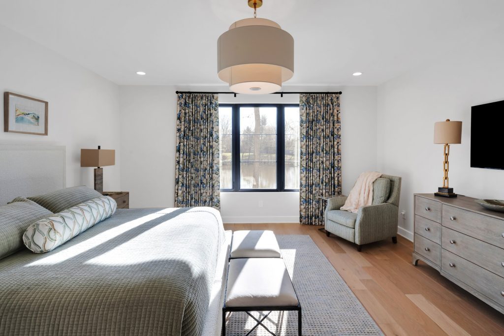Louisville modern bedroom with large bed, gray bedding, and sunlight by top custom home builders Eldridge Company.