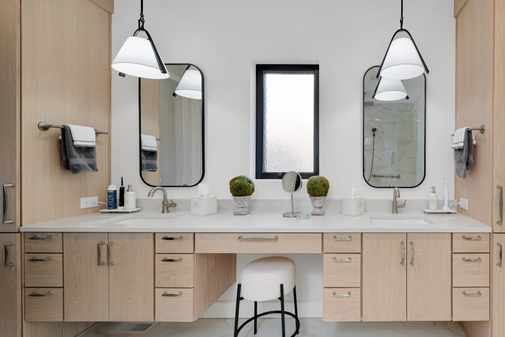 Louisville modern bathroom vanity by top custom home builders with dual mirrors, beige cabinets, and pendant lighting.