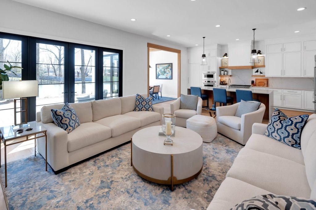 Louisville elegant living area with cream sofas, open kitchen, and airy layout by top custom home builders Eldridge Company.