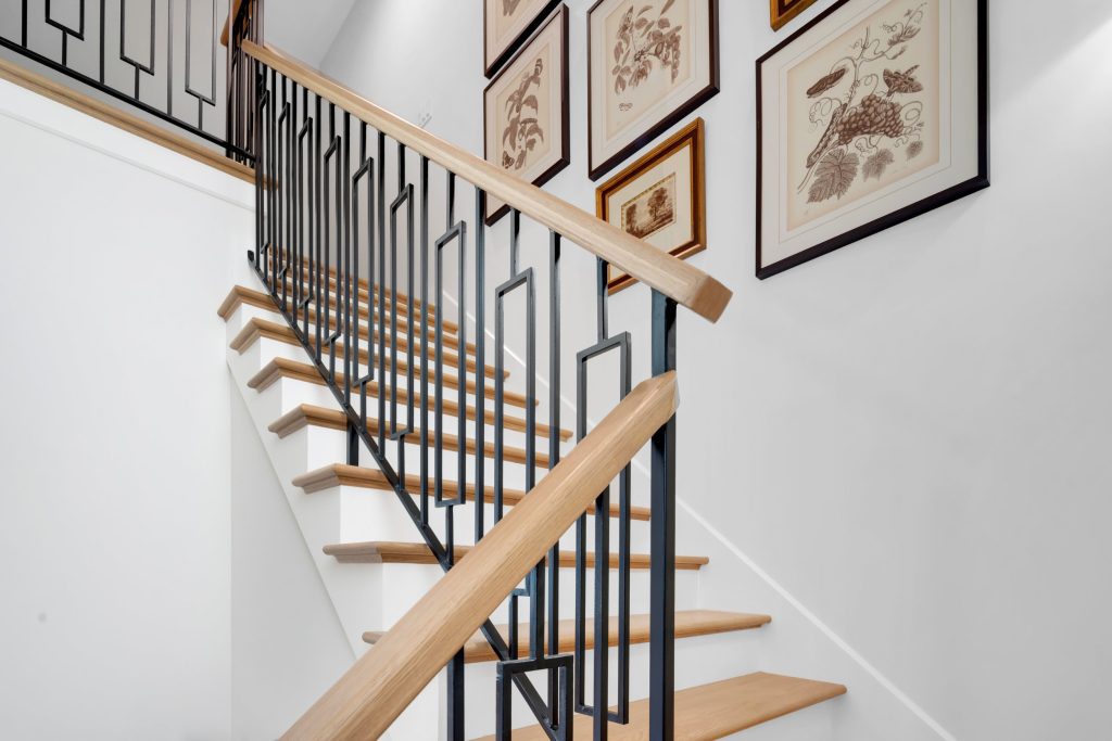 Louisville modern staircase with wooden steps, black railing, and botanical art by top custom home builders.