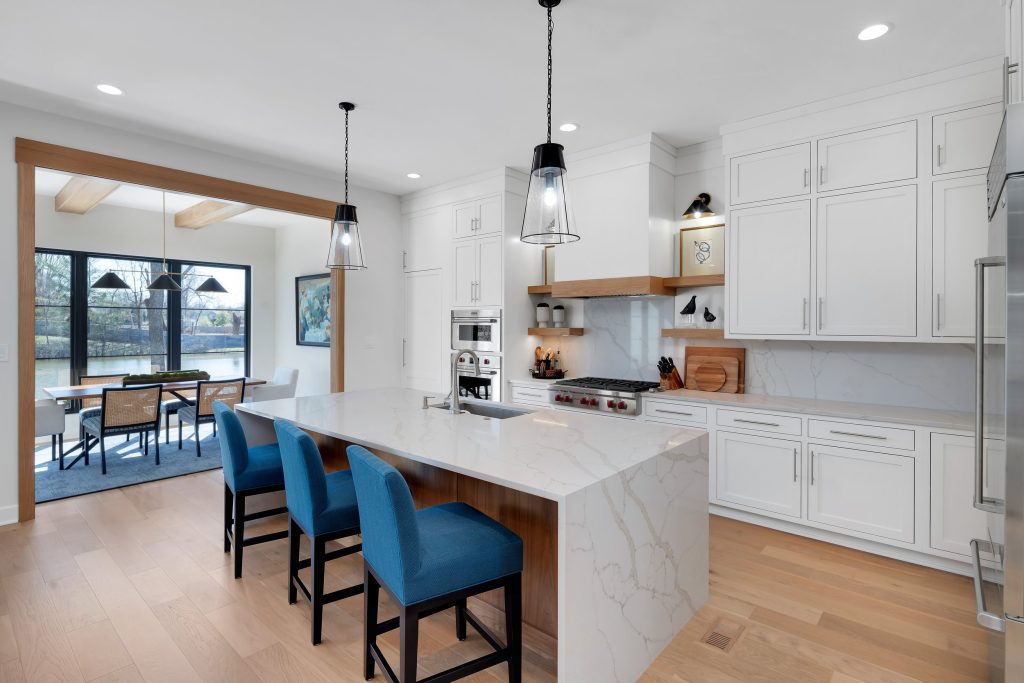 Louisville modern kitchen with white cabinets, marble island, and blue chairs by Eldridge Company, top custom home builders.