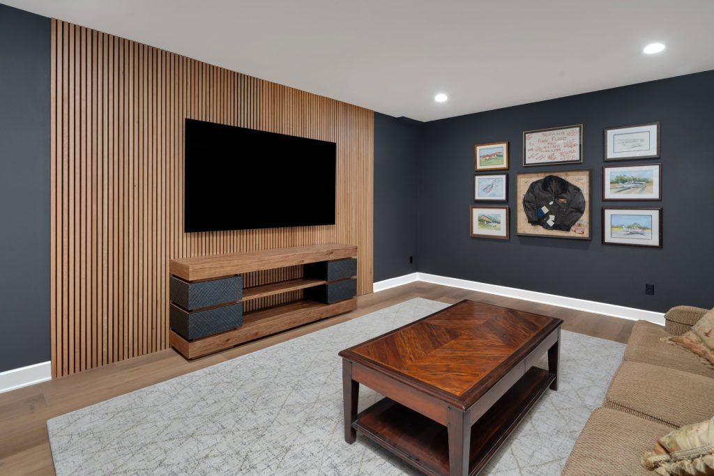 Louisville modern living room with TV on wooden slat wall, sleek console, and stylish décor by top custom home builders.