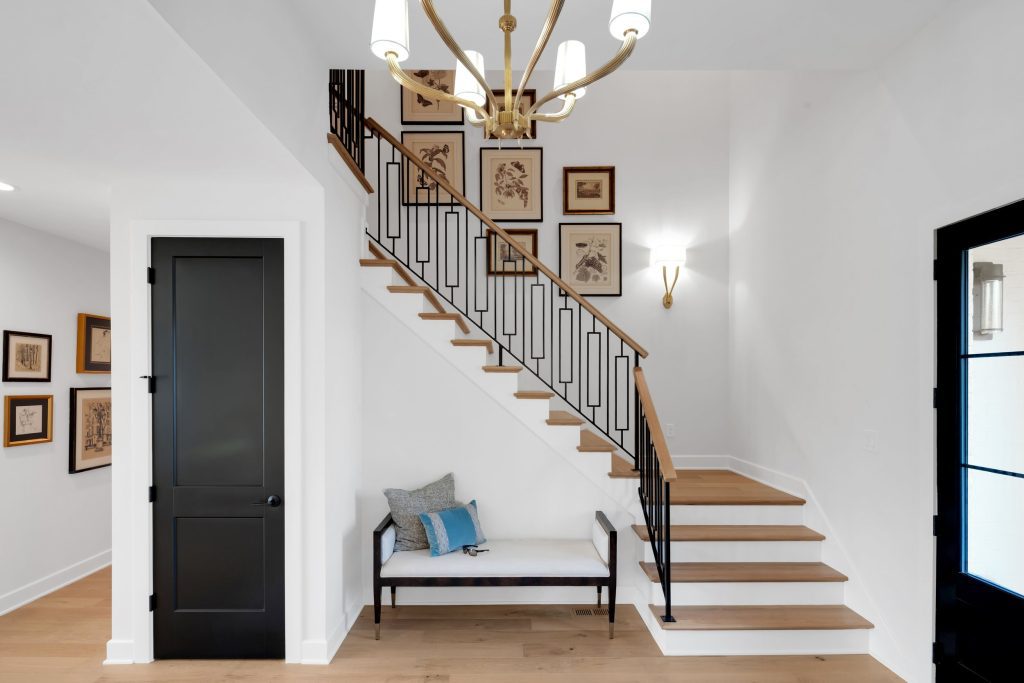Louisville modern entryway with wooden staircase, black railings, and chandelier by top custom home builders.