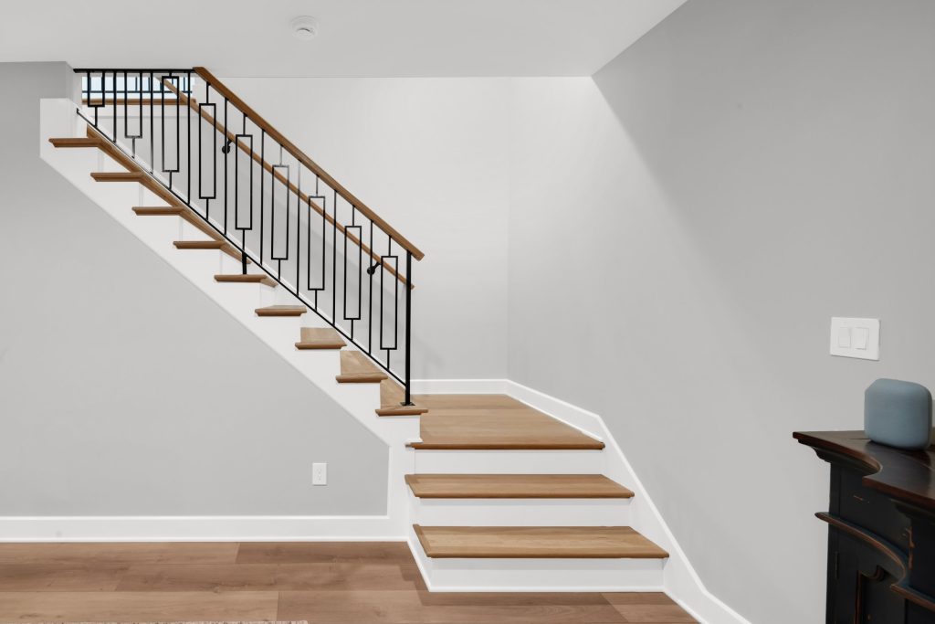 Louisville modern wooden staircase with black metal railing, sleek minimalist design by top custom home builders.