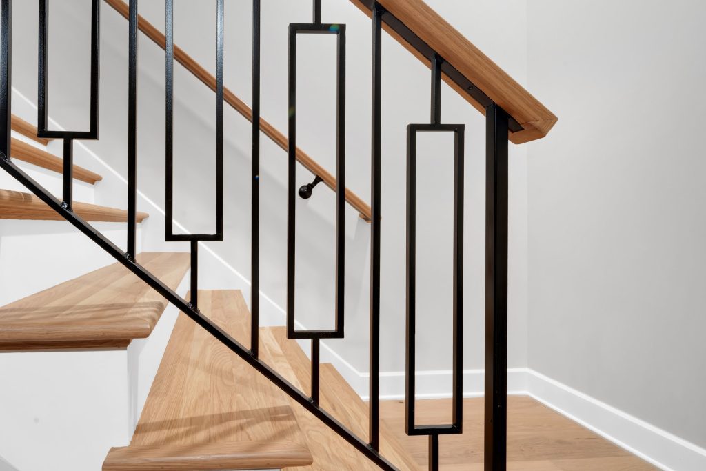 Louisville modern staircase with black metal railing and light oak steps by top custom home builders.