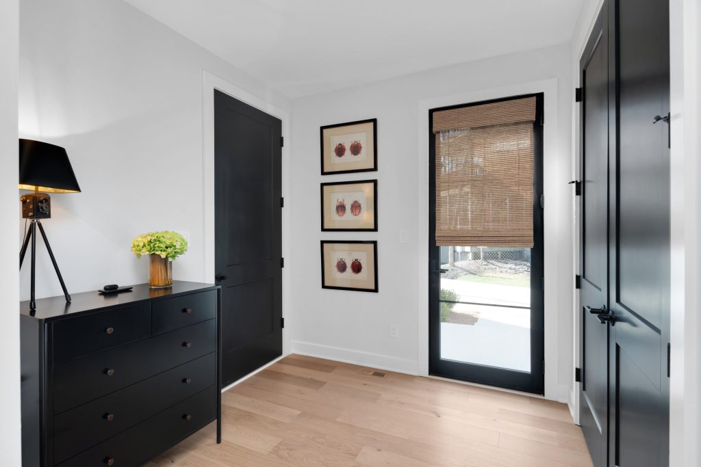 Louisville modern minimalist room with black dresser, light wood floors, and stylish decor by top custom home builders.