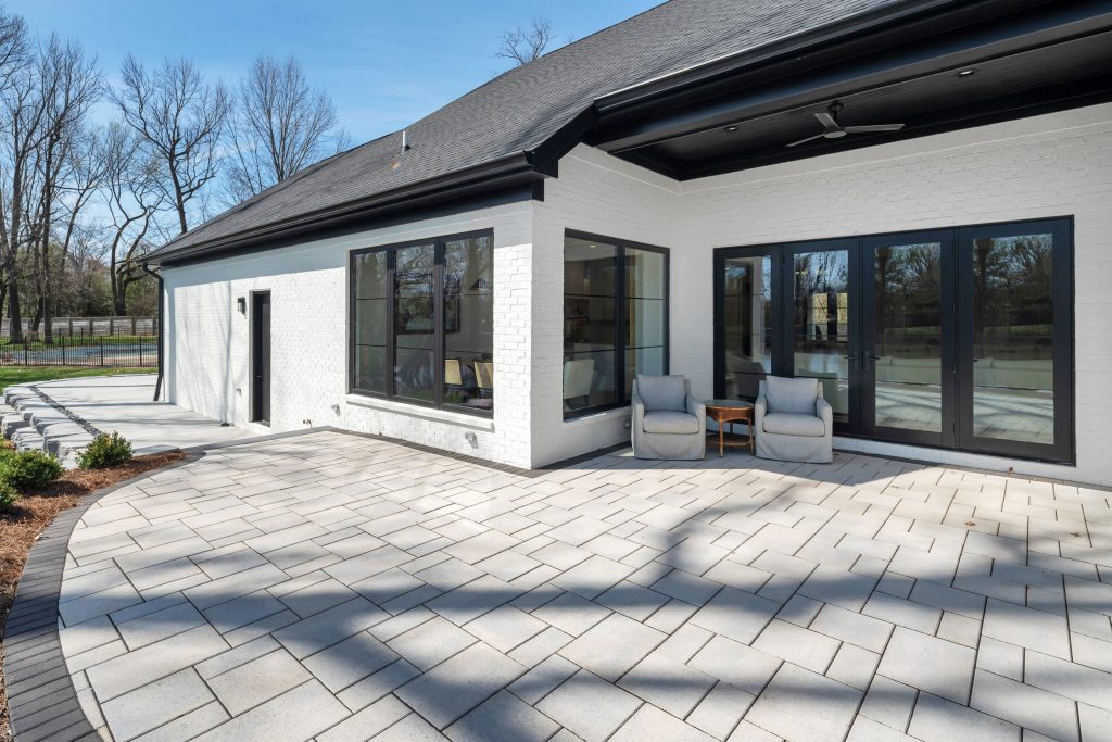 Modern Louisville white brick home with stone patio and outdoor seating by top custom home builders