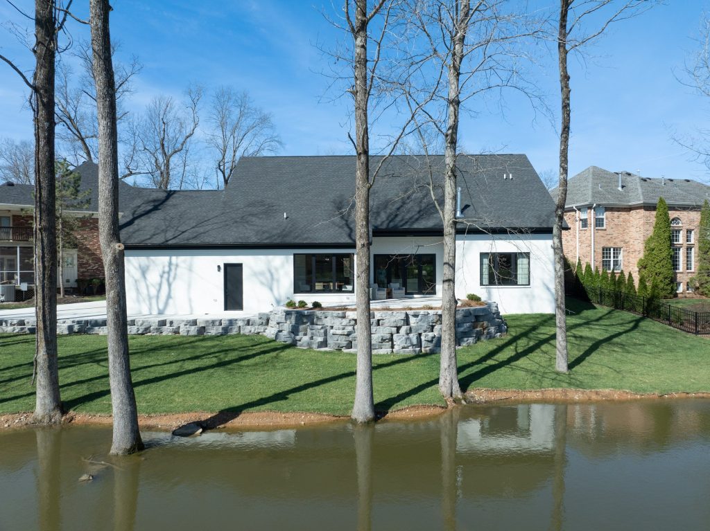 Aerial view of Louisville lakeside home surrounded by trees, designed by top modern home builders