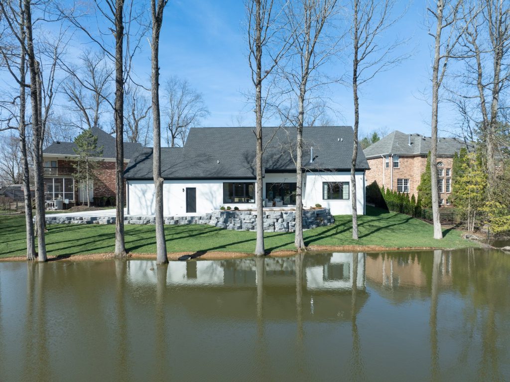 Modern Louisville white home by a pond with serene views, designed by top custom home builders