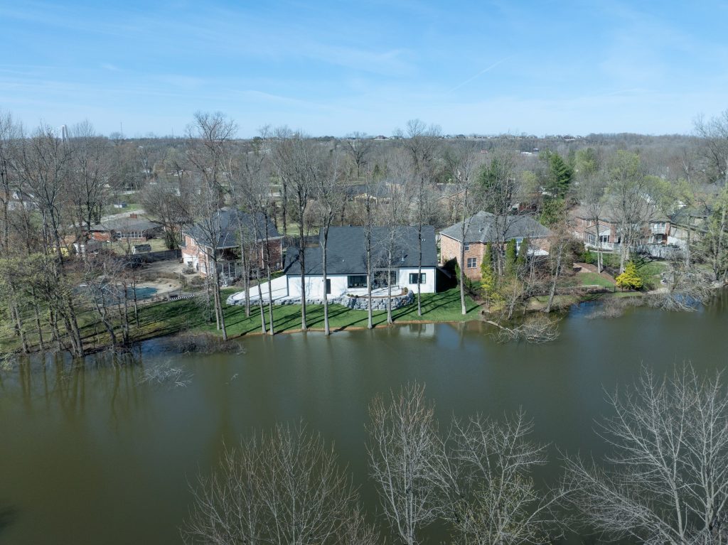 Aerial view of Louisville lakeside home surrounded by trees, designed by top modern home builders
