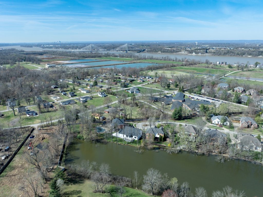 Aerial view of Louisville neighborhood with modern homes, pond, and trees by top custom home builders