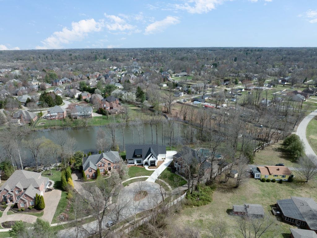 Aerial view of Louisville neighborhood with modern homes, central pond, and tree-lined streets by top custom home builders