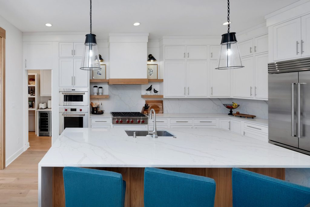 Louisville modern kitchen with white cabinets, marble island, and blue stools by Eldridge Company, top custom home builders.