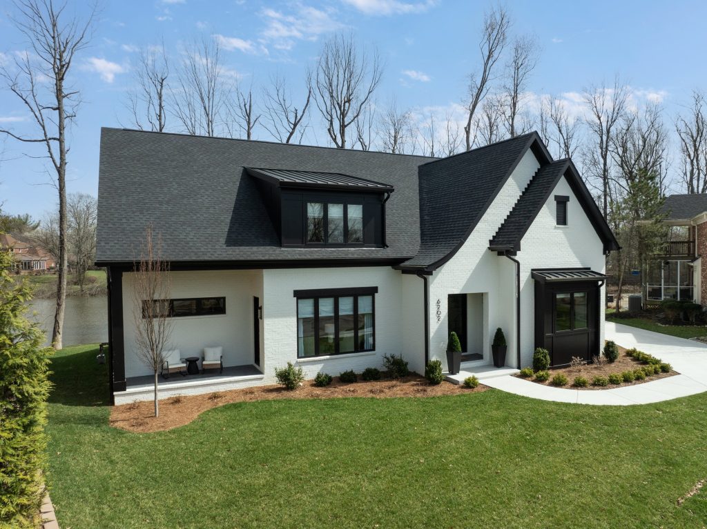 Modern Louisville home with black roof, large windows, and green lawn by top custom home builders