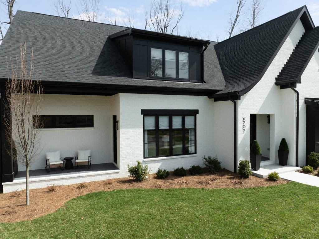 Modern Louisville white brick home with black roof, large windows, and landscaped lawn by top custom home builders