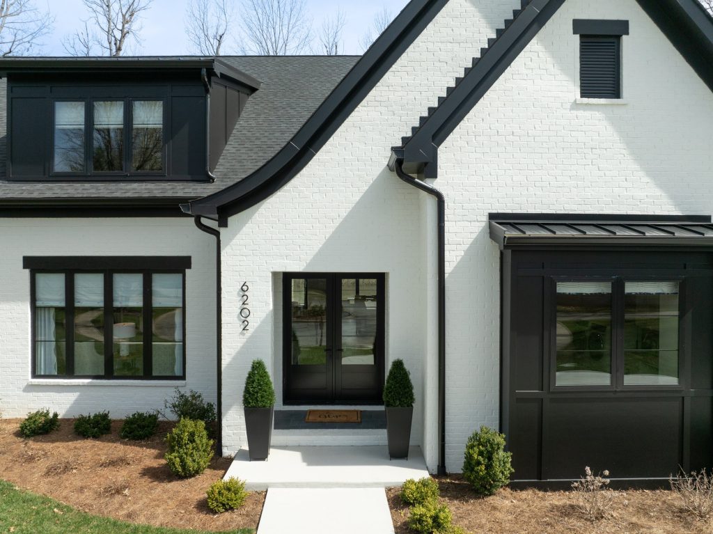 Modern Louisville white brick home with black trim, sleek front door, and landscaped walkway by top custom home builders