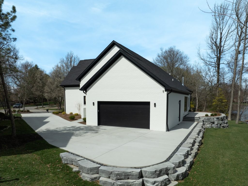 Modern Louisville home with white brick, black roof, and garage by top custom home builders