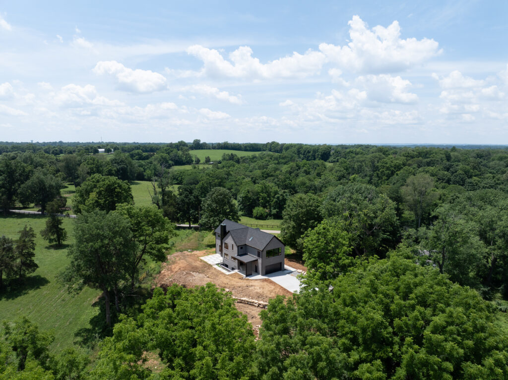 Aerial perspective of Louisville home with dark roof, green trees, and peaceful surroundings.