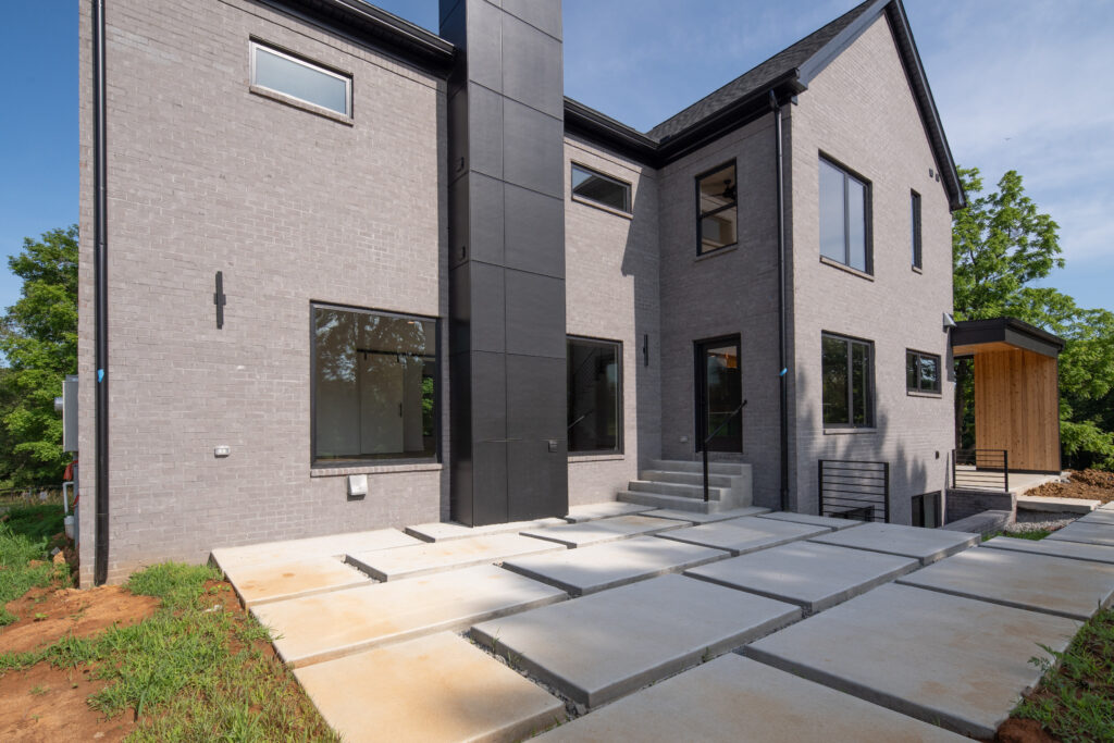Custom Louisville home with two-story modern design, concrete patio, and large windows.