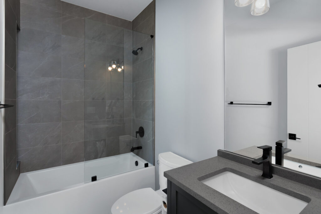 Bright Louisville bathroom featuring gray tiles, glass shower, and a sleek tub.