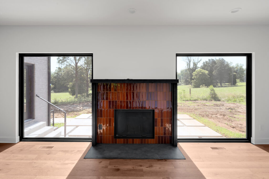 Sleek Louisville living room with central fireplace and lush green landscape views.