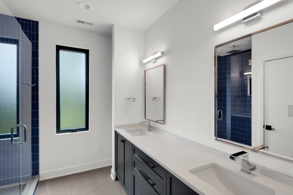 Bright Louisville bathroom with double sinks, frosted window, and stylish blue accents.