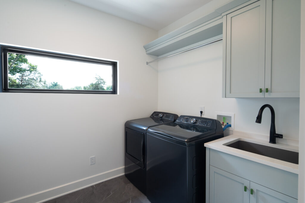 Contemporary Louisville laundry room featuring dark appliances and gray tile floor.