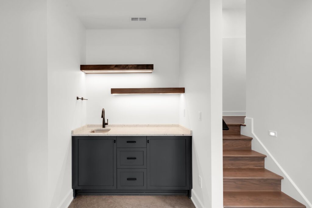 Minimalist kitchen nook in Louisville with sleek dark cabinets and wood stair accents.