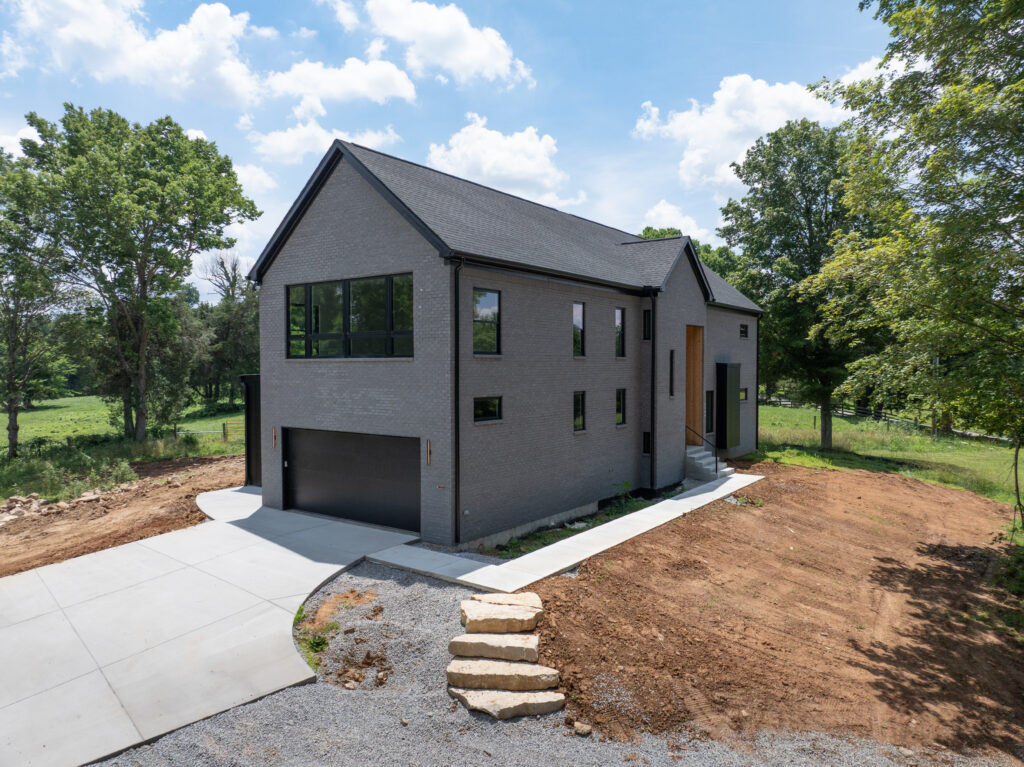 Modern gray brick Louisville house with black windows and spacious two-car garage.