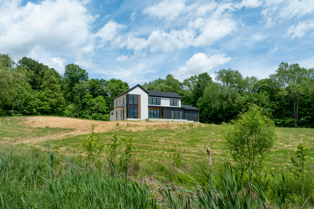 Louisville modern custom home with large windows, grassy landscape, and tranquil setting.