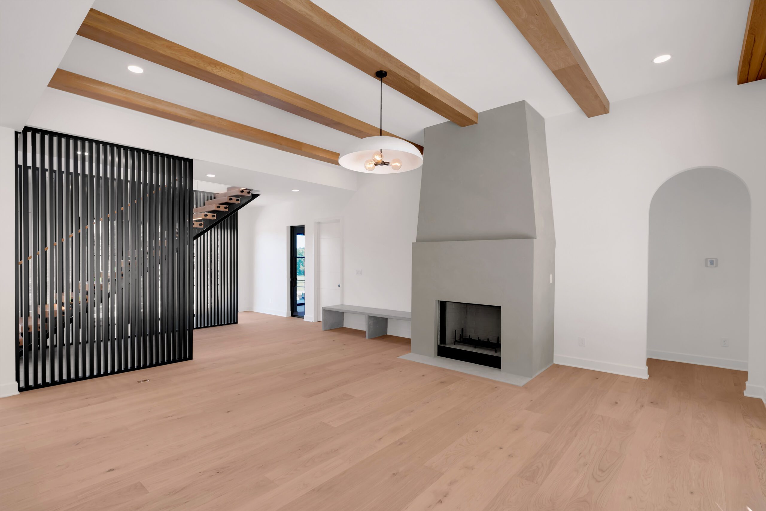 Spacious Louisville interior with gray fireplace, wood floors, and black slatted divider.