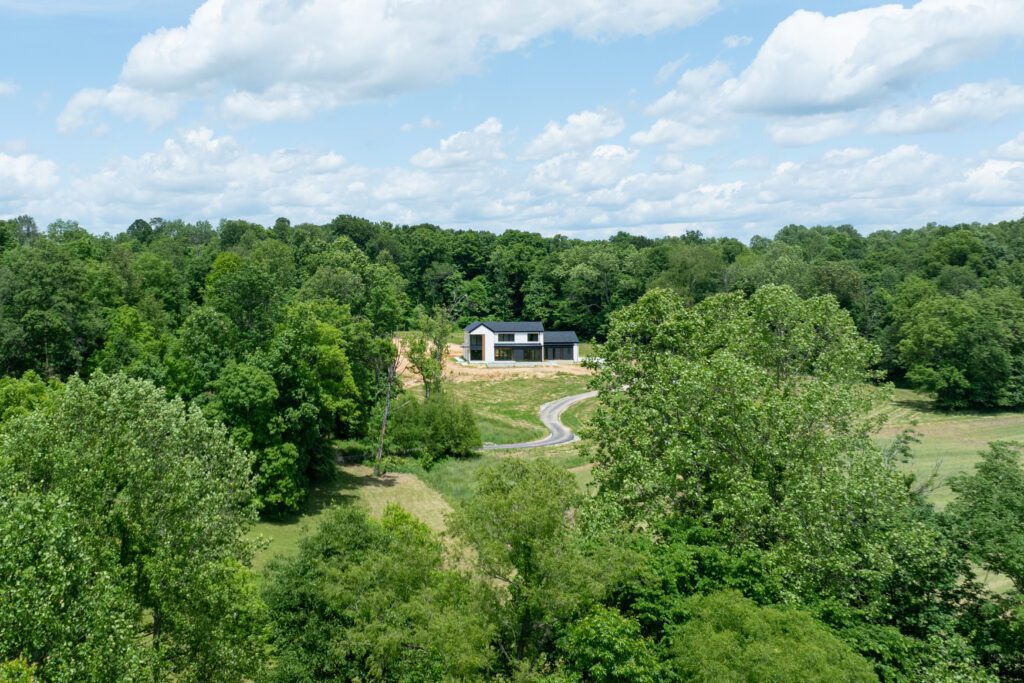 Louisville modern home exterior with dark roof, forested surroundings, and driveway access.