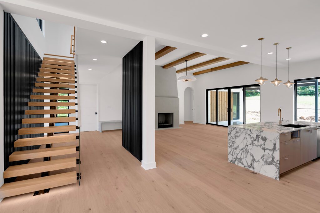 Louisville luxury open-concept design with wood staircase and marble kitchen centerpiece.