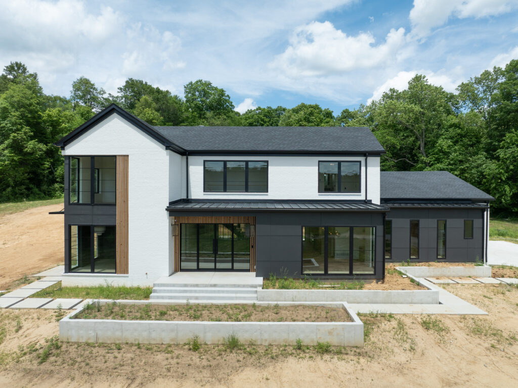 Contemporary Louisville home with sleek black accents, white brick facade, and lush green surroundings.
