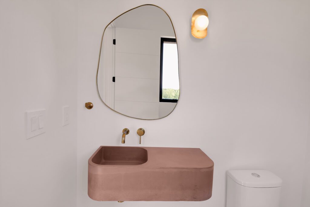 Louisville modern bathroom with bright window, warm lighting, and abstract mirror detail with concrete sink.