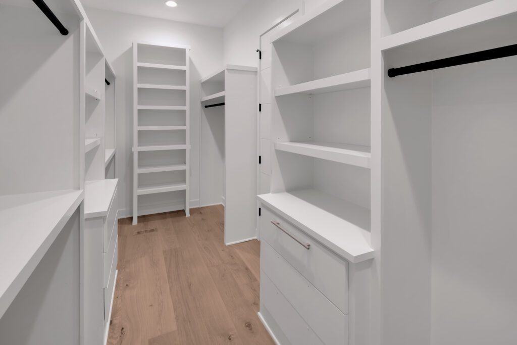 Spacious Louisville closet with white built-ins, black rods, and bright wood flooring.