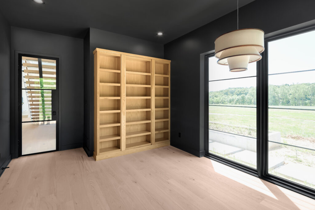 Modern Louisville home room featuring wood bookshelf, dark walls, and bright windows.