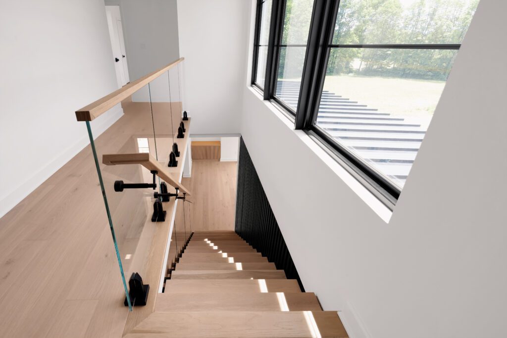 Modern Louisville staircase with light wood steps, glass railing, and black supports.