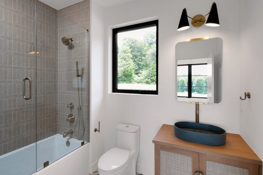Louisville modern bathroom featuring wood vanity, dark oval sink, and greenery window view.