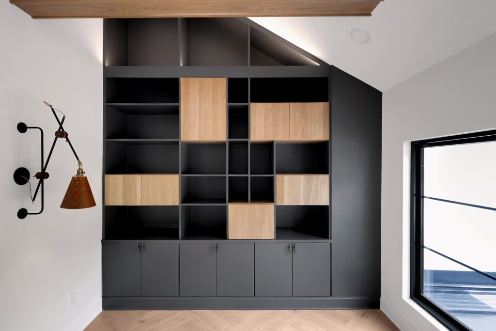 Custom Louisville modern room with pitched ceiling, dark shelving, and wooden cabinetry.